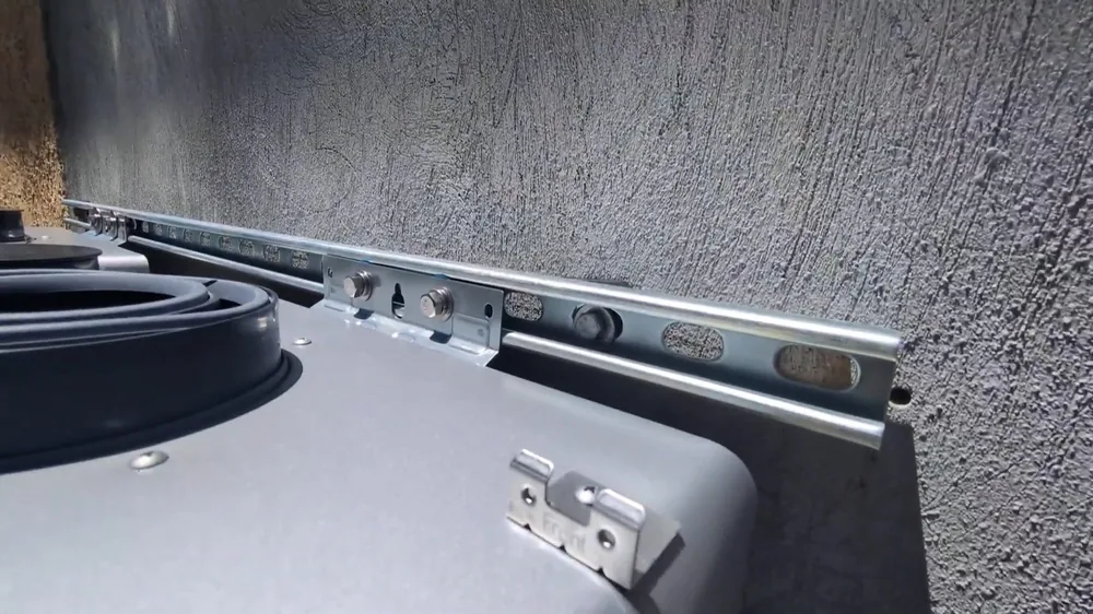 Metal mounting rail on a gray water heater jacket fixed to a textured stucco wall