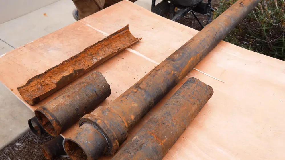 Cut sections of rusted cast iron drain pipe lying on a wooden bench
