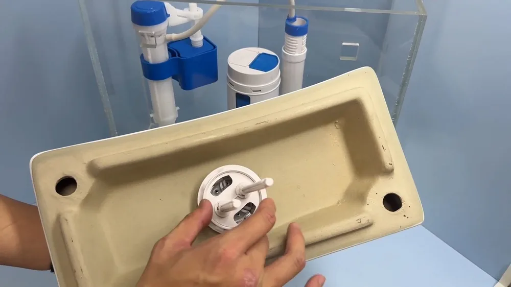 Hands fitting a part into the underside of a toilet tank lid